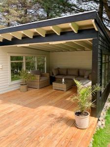 a pergola with a couch on a wooden deck at Charming Beach Cottage In Gilleleje in Gilleleje +16 photos