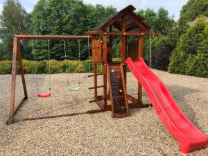 a playground with a red slide and a swing at Ranc pod Rejvizem in Zlaté Hory