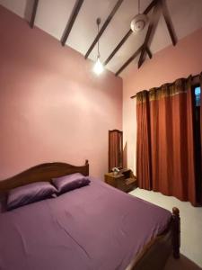 a bedroom with a bed with purple sheets and a window at Nymph Villa in Pannipitiya