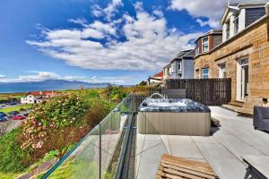 a balcony with a hot tub and a view of the ocean at Finest Retreats - Seamill Beach House in Seamill
