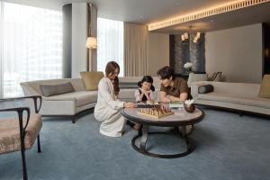 a family playing chess in a living room at Waldorf Astoria Bangkok in Bangkok
