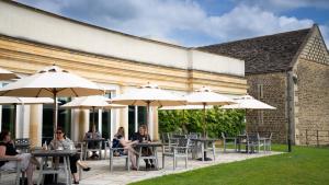 a group of people sitting at tables with umbrellas at Bowood Hotel, Spa, and Golf Resort in Chippenham