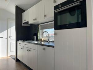 a white kitchen with a sink and a microwave at Chaletverhuur-Olmenduin in Serooskerke