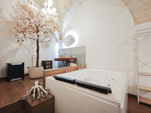 a bath tub in a room with a tree at Olympus Luxury Suites Menotti in Mola di Bari