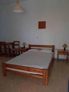 a wooden bed in a room with two tables and chairs at Pyrgis Glyfades studios in Glifades
