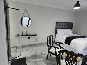 a bedroom with a bed and a mirror and a chair at Cjabaledi Private Guesthouse in Centurion