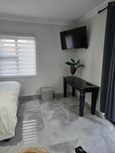 a bedroom with a table and a tv on the wall at Cjabaledi Private Guesthouse in Centurion +4 photos