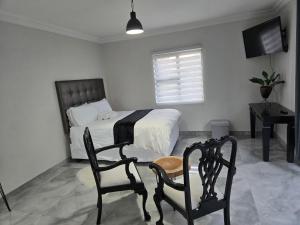 a bedroom with a bed and two chairs and a television at Cjabaledi Private Guesthouse in Centurion