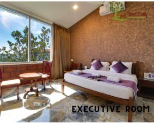 a bedroom with a large bed and a large window at Forest County Resort Mahabaleshwar in Mahabaleshwar