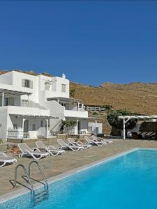a swimming pool with lounge chairs and a house at Yakinthos Suites in Mykonos