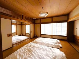 a bedroom with two beds and two windows at 伊東旅館 禅- Zen - in Ito