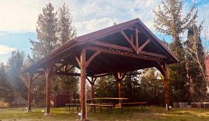 a wooden pavilion with a picnic table in a field at Domek Premium in Tleń