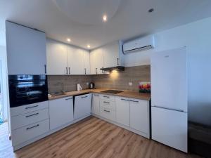 a kitchen with white cabinets and a wooden floor at Domek Premium in Tleń