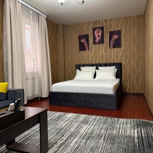 a bedroom with a bed and a desk in it at Hotel Mansuri in Almaty