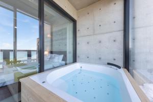 a large bath tub in a room with a large window at Goseong Romiet Pension in Goseong