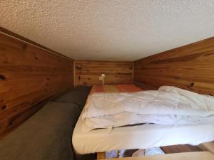 a bed in a room with a wooden wall at Appartement Pyrénées 2000 in Bolquere Pyrenees 2000 +4 photos