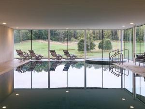 a room with a pool with chairs and a lot of windows at Bowood Hotel, Spa, and Golf Resort in Chippenham