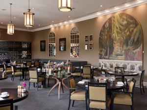 a restaurant with tables and chairs and a large painting at Bowood Hotel, Spa, and Golf Resort in Chippenham