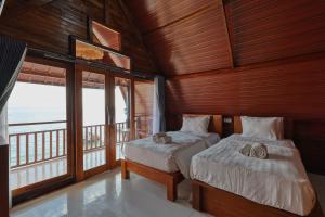 two beds in a room with a view of the ocean at Road Beach Cottages in Nusa Penida