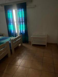 a bedroom with a bed and a window with curtains at Galini Pension in Ios Chora