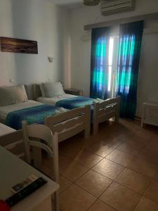 a bedroom with two beds and a window with blue curtains at Galini Pension in Ios Chora