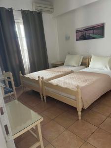 two beds in a room with a table and a bed at Galini Pension in Ios Chora