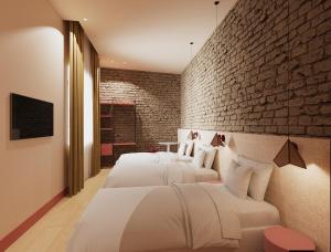 two beds in a room with a brick wall at BYPILLOW Naranjo in Seville +5 photos