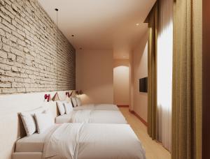 a bedroom with two beds and a brick wall at BYPILLOW Naranjo in Seville
