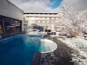 a swimming pool in front of a building in the snow at Spa Hotel Ata in Varshets