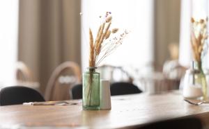 a vase with flowers in it sitting on a table at DORMERO Hotel Freiburg in Freiburg im Breisgau