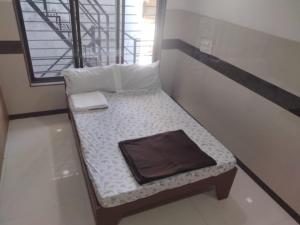 a small bed sitting in a room with a window at Balaji rooms&domentry in Surat