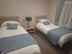 a bedroom with two beds and a lamp on a night stand at Crescent Lodge in Forton