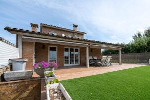 a house with a patio with chairs on a lawn at Luxury Getaway in Girona in Riudellots de la Selva