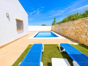 a backyard with a swimming pool and two blue benches at Chalet Playa Roche in Roche
