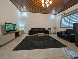 a living room with a couch and a tv at Baobab Lodge Douala - Makepe in Douala