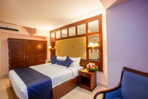 a hotel room with a bed and a chair at Holiday Hotel in Cherai Beach +16 photos