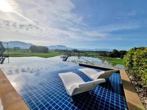 a swimming pool with two white chairs on top of it at Sangthong Resort at Chiang Klang in Chiang Klang