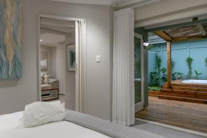 a bedroom with a bed and a balcony with a tub at Lagoon Point Lodge in Knysna