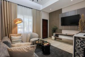 a living room with a television and a couch and chairs at Ditsametse Luxe Suites in Gaborone
