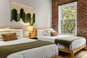 two beds in a room with a brick wall at The West 142nd Street Apartments - Manhattan NYC in New York