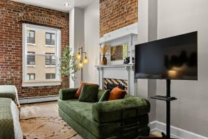 a living room with a green couch and a flat screen tv at The West 142nd Street Apartments - Manhattan NYC in New York