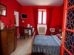 een slaapkamer met rode muren, een bed en een bureau bij Chambre d'Hotes La Brunetière in Gréoux-les-Bains