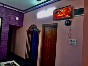 a room with a television on the wall and a door at Anna Miracle Homestay in Kāsarkod +26 photos