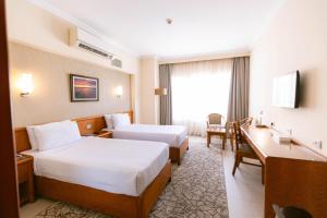 a hotel room with two beds and a desk at The Grand Plaza Hotel Smouha in Alexandria