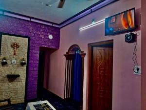 a room with purple walls and a door with a television at Anna Miracle Homestay in Kāsarkod