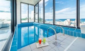 a swimming pool with two drinks in a building at Gangneung Skaria Poolvilla in Gangneung