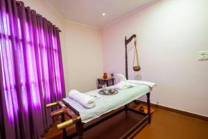 a hospital bed in a room with purple curtains at Holiday Hotel in Cherai Beach