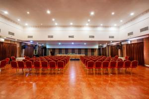 a large room with red chairs and a stage in it at Holiday Hotel in Cherai Beach