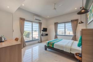 a bedroom with a bed and two large windows at Treebo Premium Vapr Ashok Nagar in Chennai