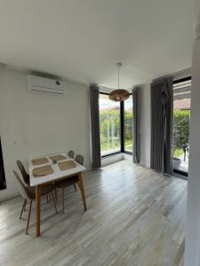 a living room with a table and chairs and windows at Вила Солана - Villa Solana in Lozenets